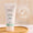 En vit tub med Green People Fruit Scrub Exfoliator står på en träbricka bredvid en ikon för Dermatologically Tested.