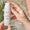 Händer som håller en flaska Green People Firming Face & Neck Serum med ett Dermatologically Tested-sigill som överlägg.