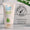 En vit tub med Organic Babies Baby Wash & Shampoo Scent Free står bredvid en Dermatologically Tested-logotyp mot en vit kakelvägg.