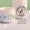 En öppen vit burk med Organic Babies Mum & Baby Rescue Balm står på en marmoryta bredvid en stämpel för dermatologiskt testad.