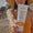 A hand holds a tube of Edelweiss Sun Cream with Tan Accelerator SPF15 on a sunny beach in front of a woman in a straw hat.