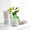 En vit burk med Organic Babies Mum & Baby Rescue Balm står på en ljus yta bredvid en leksaksmus i trä och en grön växtvas.