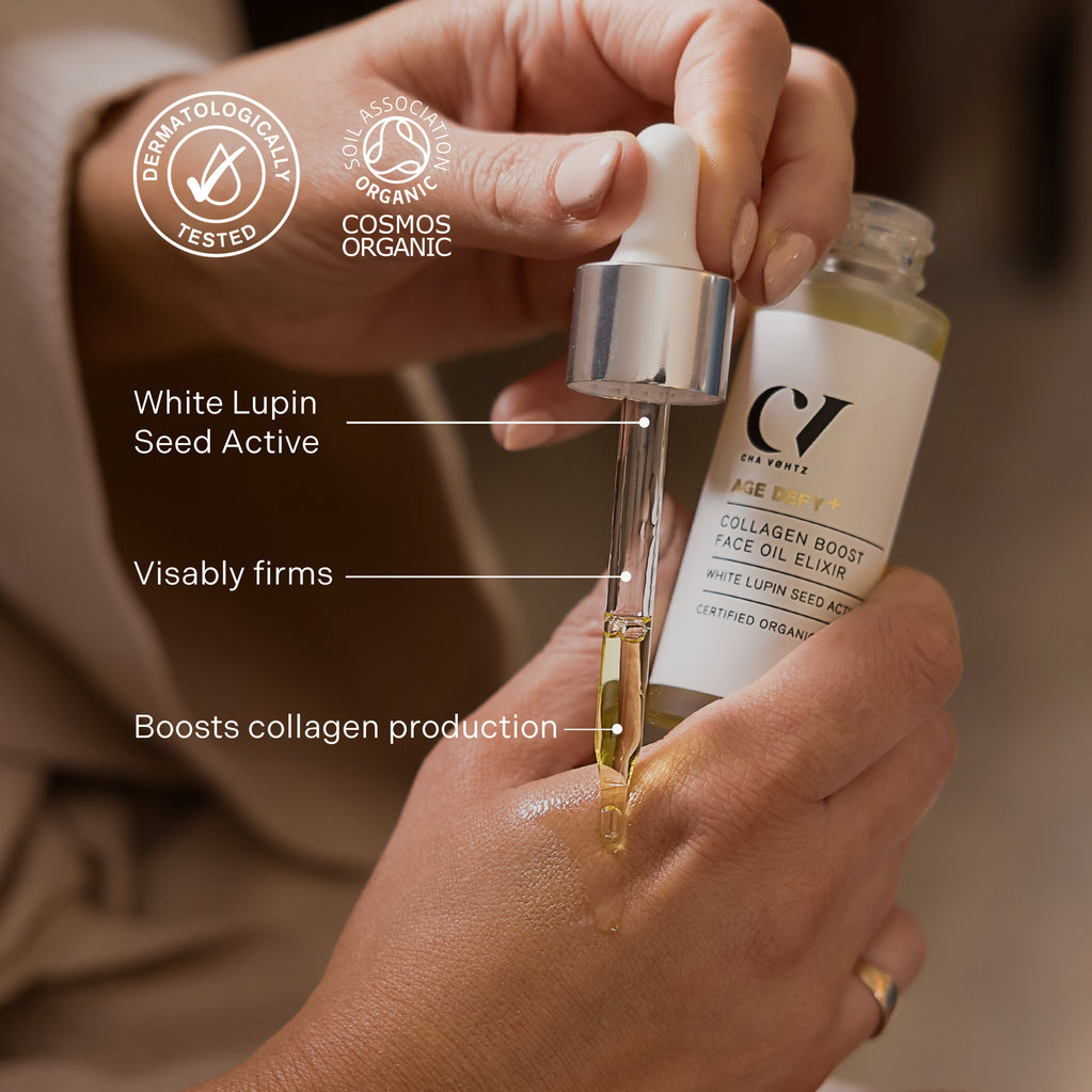 Hands use a glass dropper to apply golden Age Defy+ Collagen Boost Face Oil Elixir onto skin.