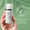 En hand håller en flaska Age Defy+ Tinted DD Moisturiser SPF 15 mot en grön bakgrund med ett sigill för dermatologiskt testad.