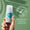 En hand håller en flaska Oy Deodorant mot en mjukt grön bakgrund bredvid ett emblem för dermatologiskt testad.