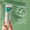 En hand håller en tub med Oy Clear Skin Purifying Serum mot en mjukt grön bakgrund med ett märke för dermatologiskt testad.